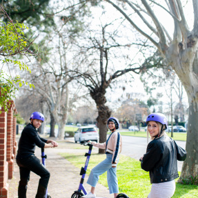 Three happy young people riding Beam Adelaide Scooters